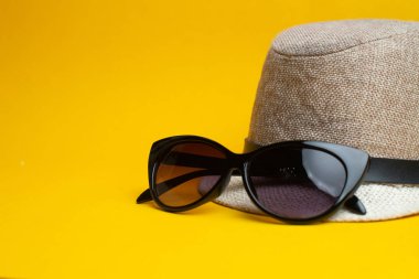 Sarı backgro üzerinde yaz aksesuarları, panama şapka ve güneş gözlüğü