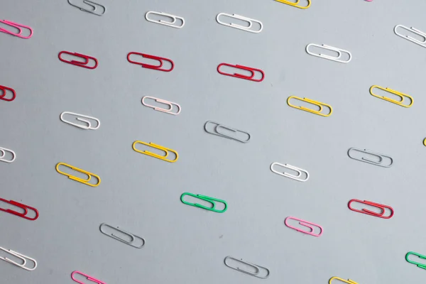 Multicolor paper clips on grey background. Back to school. Vario