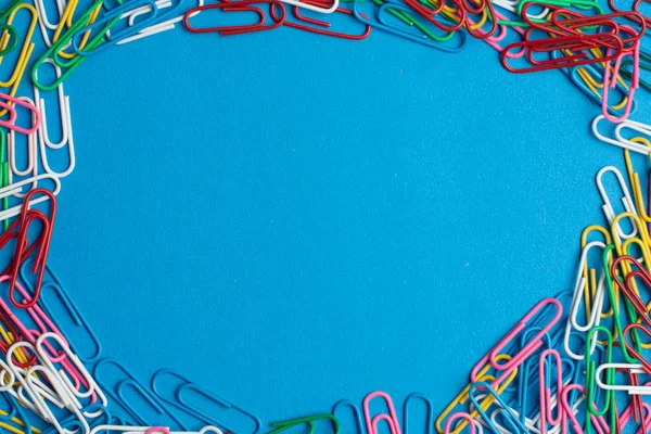 Colorful paper clips on blue background. Back to school. Various