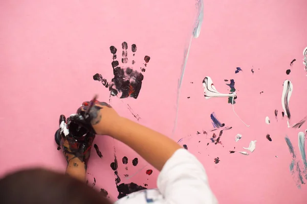 Mãos de um menino pintando com aquarelas em papel rosa sh — Fotografia de Stock