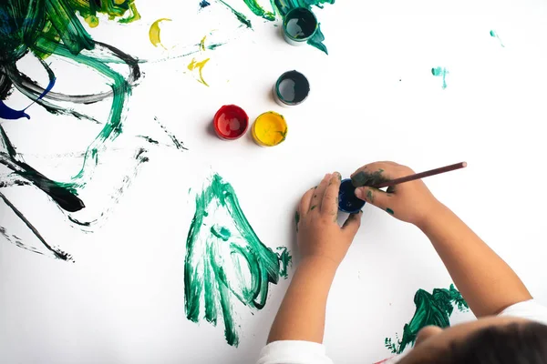 Ruce malého chlapce, který maluje s akvarovými barvami na bílém papíře — Stock fotografie