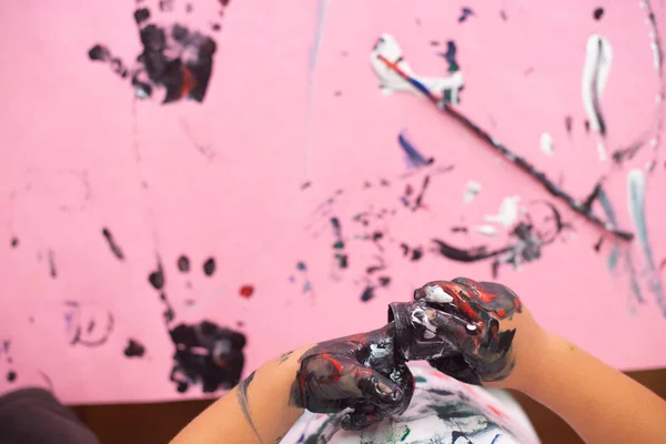 Manos de un niño pequeño pintando con acuarelas sobre papel rosa sh —  Fotos de Stock