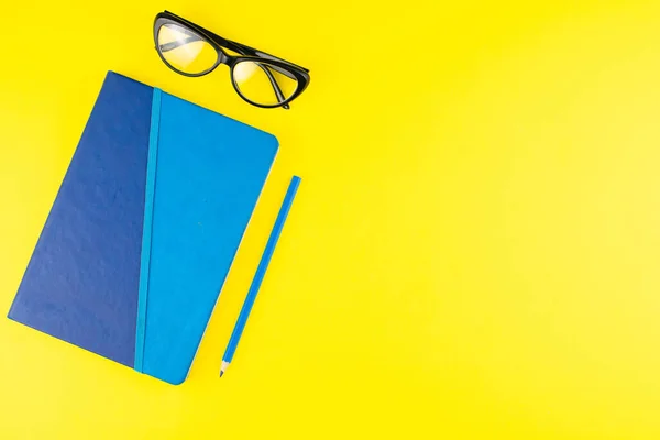 Bloc Notas Azul Lápiz Gafas Negras Sobre Fondo Amarillo Acostado —  Fotos de Stock