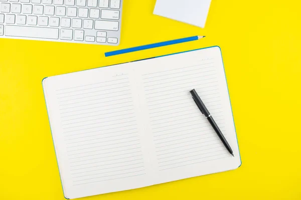 Schwarzer Stift Notizblock Bleistift Und Tastatur Auf Gelbem Hintergrund Flach — Stockfoto