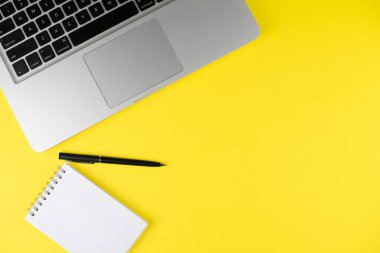 Laptop, sarı arka planda siyah kalemli not defteri planlayıcısı. Düz yatıyordu. Uzayı kopyala Ofiste işyeri.   