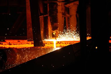 Meşalenin yanındaki çelik bölmeler metalürjik bitkileri kesiyor. Metalurjik üretim, ağır sanayi, mühendislik, çelik yapımı. 