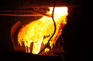 Çelik fabrikasına dökülen sıcak çelik. Kepçeden erimiş metal döküldü. Metalurjik üretim, ağır sanayi, mühendislik, çelik yapımı.
