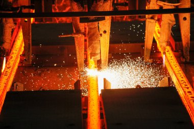 Meşalenin yanındaki çelik bölmeler metalürjik bitkileri kesiyor. Metalurjik üretim, ağır sanayi, mühendislik, çelik yapımı