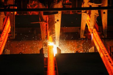 Meşalenin yanındaki çelik bölmeler metalürjik bitkileri kesiyor. Metalurjik üretim, ağır sanayi, mühendislik, çelik yapımı