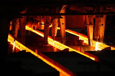 Meşalenin yanındaki çelik bölmeler metalürjik bitkileri kesiyor. Metalurjik üretim, ağır sanayi, mühendislik, çelik yapımı