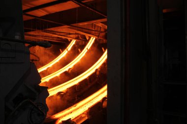 Erimiş çeliğin dökülmesinden sonra, kırmızı çelik çubuklar. Devamlı döküm makinesi. Demirci ve metalurji endüstrisinin arka planı.