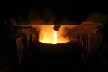 Çelik fabrikasına dökülen sıcak çelik. Kepçeden erimiş metal döküldü. Metalurjik üretim, ağır sanayi, mühendislik, çelik yapımı.