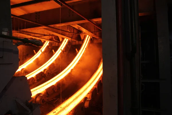 Erimiş çeliğin dökülmesinden sonra, kırmızı çelik çubuklar. Devamlı döküm makinesi. Demirci ve metalurji endüstrisinin arka planı.