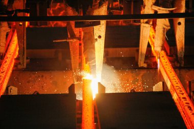 Meşalenin yanındaki çelik bölmeler metalürjik bitkileri kesiyor. Metalurjik üretim, ağır sanayi, mühendislik, çelik yapımı