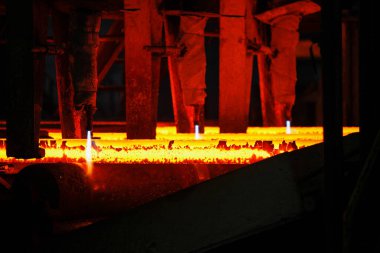 Meşalenin yanındaki çelik bölmeler metalürjik bitkileri kesiyor. Metalurjik üretim, ağır sanayi, mühendislik, çelik yapımı
