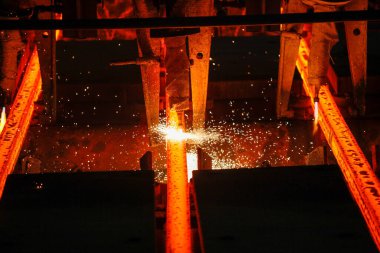 Meşalenin yanındaki çelik bölmeler metalürjik bitkileri kesiyor. Metalurjik üretim, ağır sanayi, mühendislik, çelik yapımı
