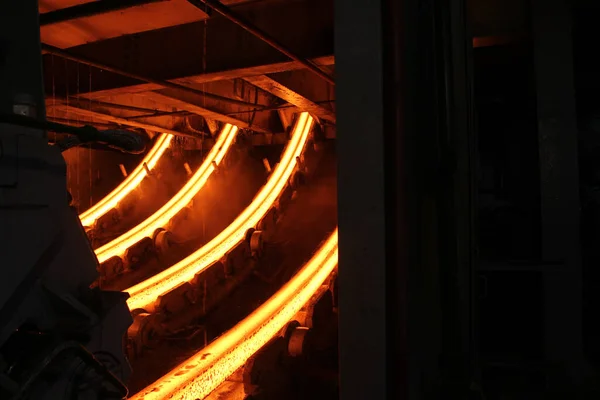 Erimiş çeliğin dökülmesinden sonra, kırmızı çelik çubuklar. Devamlı döküm makinesi. Demirci ve metalurji endüstrisinin arka planı.
