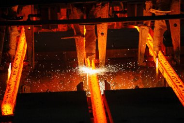 Meşalenin yanındaki çelik bölmeler metalürjik bitkileri kesiyor. Metalurjik üretim, ağır sanayi, mühendislik, çelik yapımı