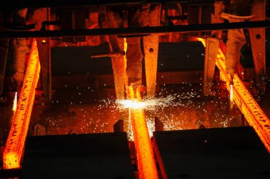 Meşalenin yanındaki çelik bölmeler metalürjik bitkileri kesiyor. Metalurjik üretim, ağır sanayi, mühendislik, çelik yapımı