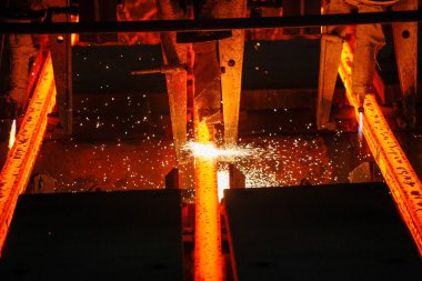 Meşalenin yanındaki çelik bölmeler metalürjik bitkileri kesiyor. Metalurjik üretim, ağır sanayi, mühendislik, çelik yapımı