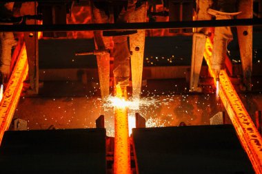 Meşalenin yanındaki çelik bölmeler metalürjik bitkileri kesiyor. Metalurjik üretim, ağır sanayi, mühendislik, çelik yapımı