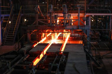 Erimiş çeliğin dökülmesinden sonra, kırmızı çelik çubuklar. Devamlı döküm makinesi. Demirci ve metalurji endüstrisinin arka planı.