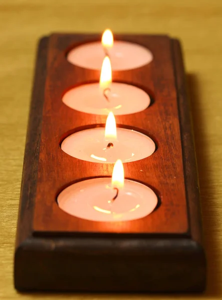 Burning tea light candles in wooden holder.