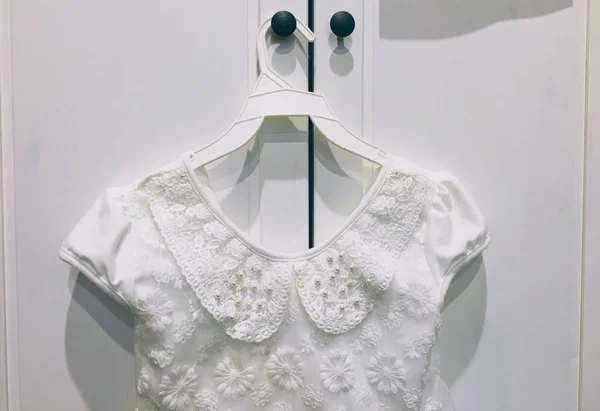 White trim dress for little girl on a hanger handing on a white wardrobe