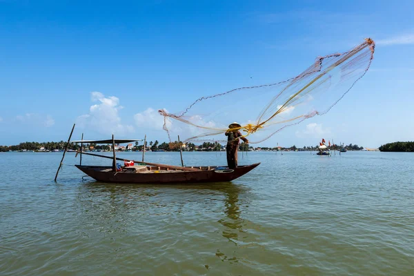 A traditional fisherman is throwing a fishing net at Hoi An in Vietnam