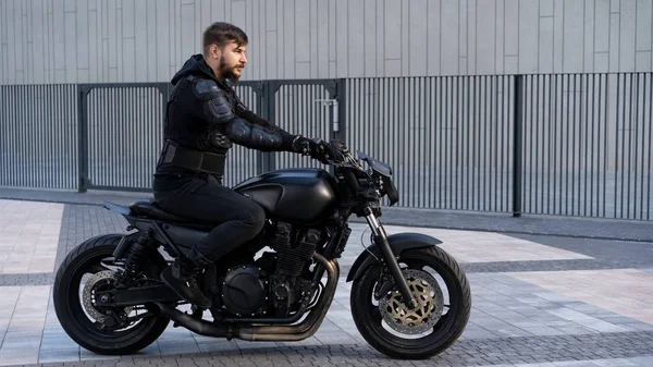Cara em uma motocicleta preta ficar na estrada — Fotografia de Stock