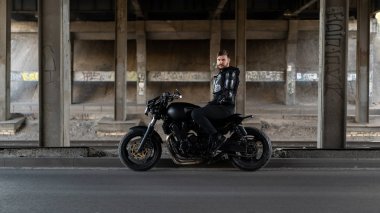 Adam bir siyah motosiklet motosiklet üzerinde köprü altında kal