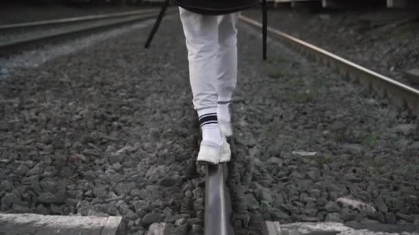 Девушка с гитарой на спине на железной дороге — стоковое видео