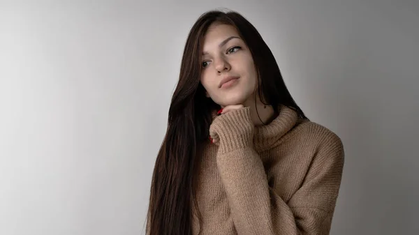 ライトグレーの背景に暖かいニットのセーターの豪華な若いブルネットの少女 — ストック写真