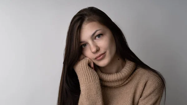 Prachtige jonge brunette vrouw in warme gebreide trui op lichte grijze achtergrond — Stockfoto