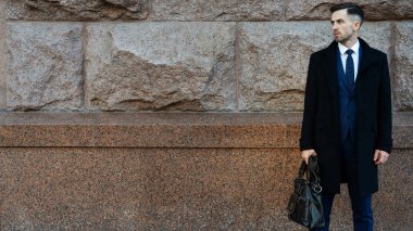 Duvarın yanında bir çanta holding iş adamı. Arka plan veya afiş iş tema arayın