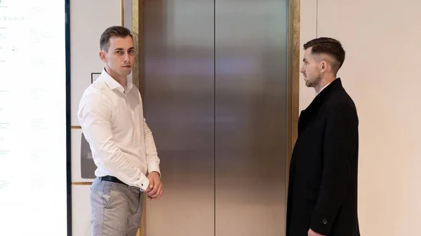 Two businessmen standing near elevator. Business people near a elevator in the office and look