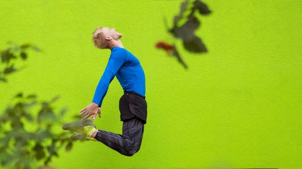 Jovem homem forte pulando no fundo verde — Fotografia de Stock
