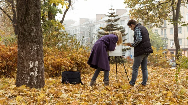 Giovane artista ragazza insegnando un improvviso come disegnare nel parco autunnale — Foto Stock