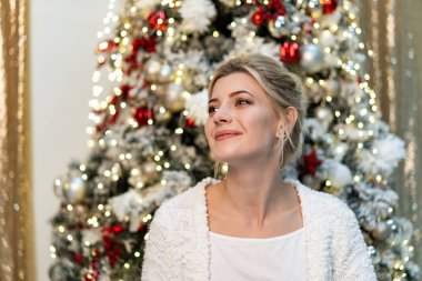Güzel sarışın kız beyaz kazak Noel ağacının yanında poz portresi yarım uzunluk