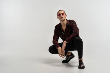 Siyah kot rahat giyinmiş genç adam çömelmiş ve poz