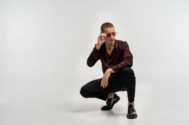 Siyah kot rahat giyinmiş genç adam çömelmiş ve poz