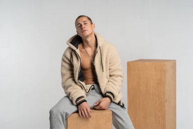 Bir adam gri pantolon ahşap bir küp üzerinde oturan çıplak bir gövde ile