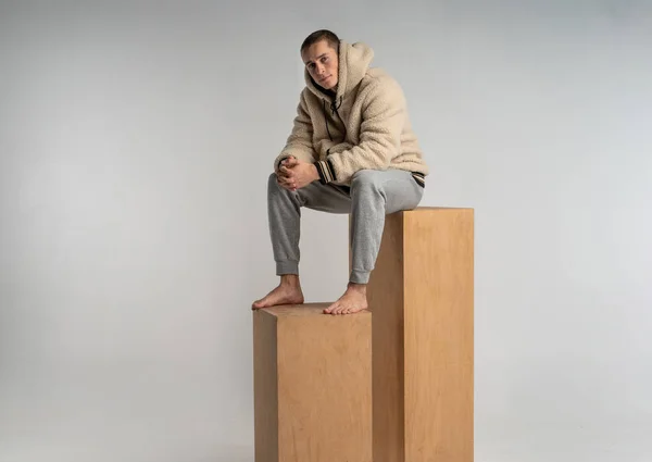 Modelo masculino en ropa deportiva siiting en cubo de madera mirando a la cámara — Foto de Stock