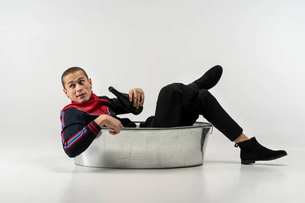 Modelo guapo masculino con corte de pelo corto en ropa casual sentado en el baño de metal — Foto de Stock