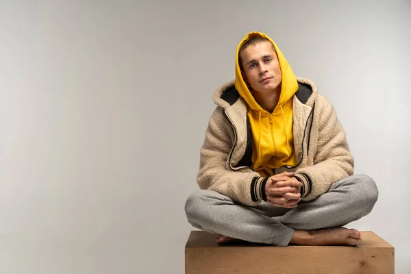 Hombre guapo con capucha amarilla sentado en cubo de madera — Foto de Stock