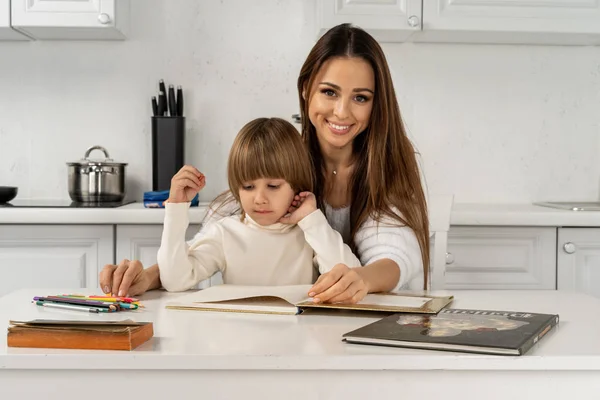 Porträtt av en leende ung söt mamma och son ritning hemma på köket — Stockfoto