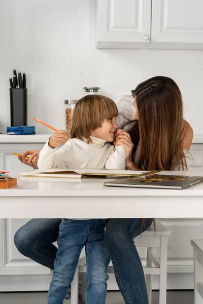 Porträtt av en leende ung söt mamma och son ritning hemma på köket — Stockfoto