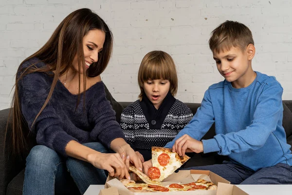 Lycklig familj i tröjor som äter pizza hemma — Stockfoto