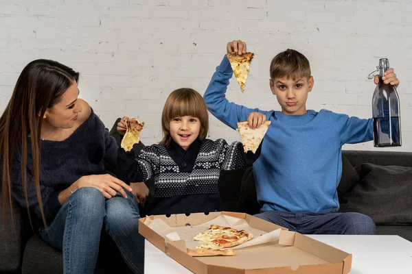 Vacker ung brunet mamma med lite söner poserar tillsammans med pizza — Stockfoto