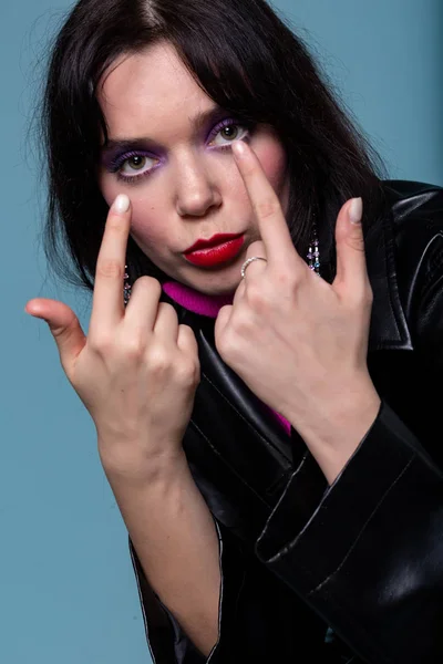 Indoor shot of attractive european girl with black hair pointing fingers up